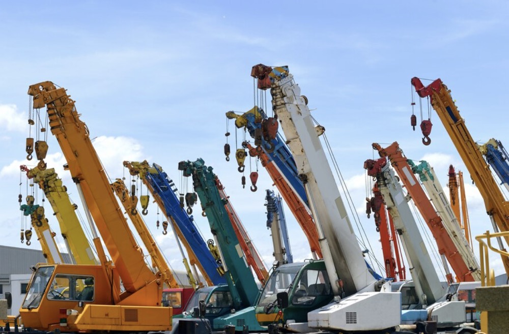 Two-workers-checking-work-at-a-construction-site-with-heavy-construction-machinery-in-the-background